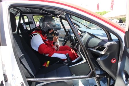 Racers get strapped into the racing seat with a 4-point harness by one of the marshals.